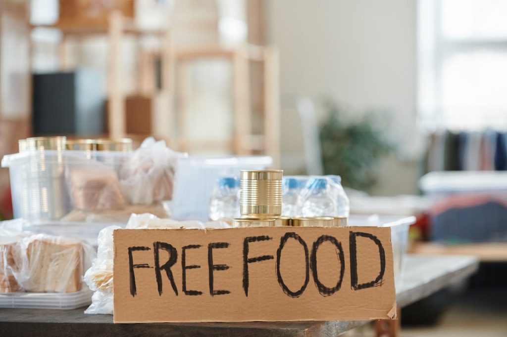 a-cardboard-with-label-6995018 Indoor view of a donation table with free food and canned goods.